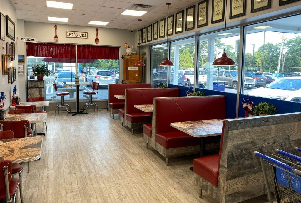 Empty diner interior with red booths, wood floors, and large front windows