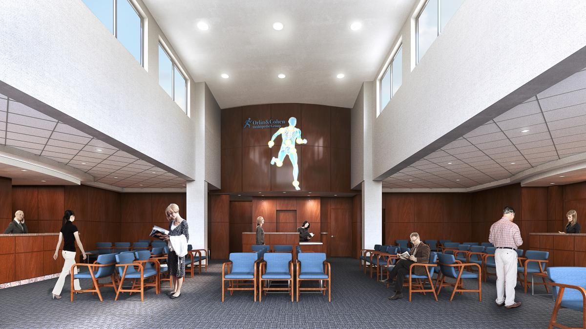 Wide lobby with people seated at tables beneath a large wall sculpture and high windows