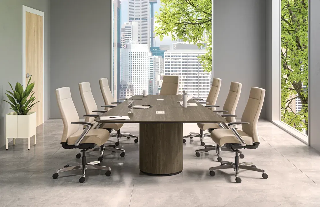 Modern conference room with a long table, beige swivel chairs, and large windows overlooking city buildings.