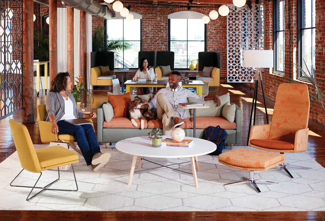 Modern lounge with people chatting on colorful chairs around a round table in a bright, patterned interior