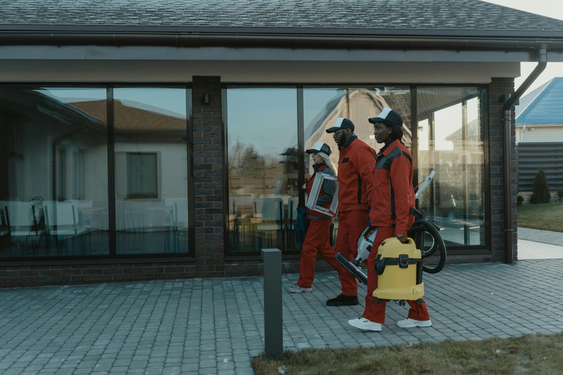 A group of men are walking down a sidewalk in front of a house.