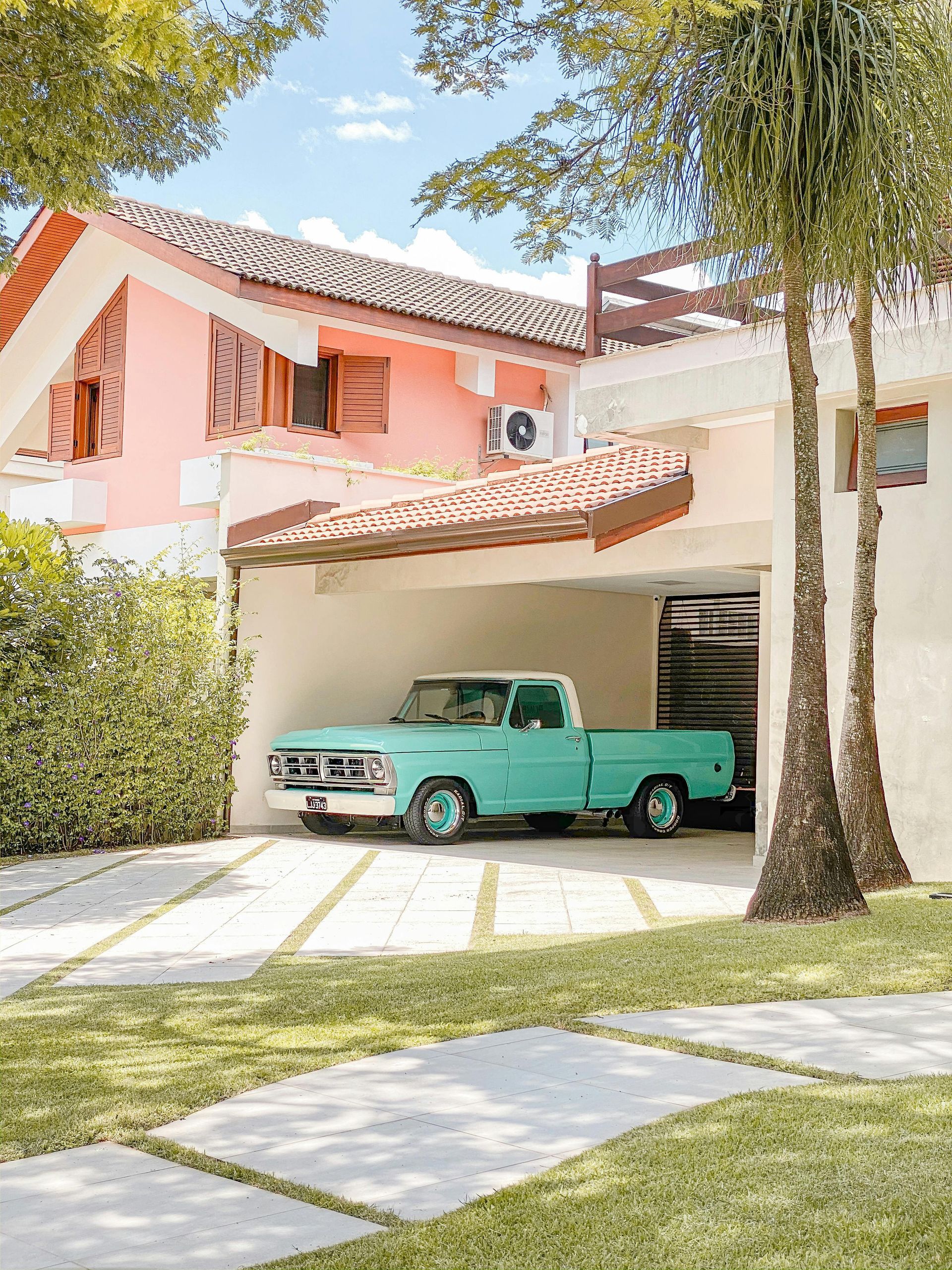 A blue truck is parked in the driveway of a house.