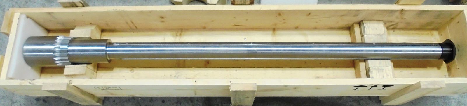 Una lunga asta di metallo è inserita in una cassa di legno, tenuta ferma da blocchi di supporto.