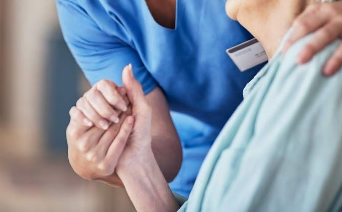 Una donna in camice blu sorride a una donna