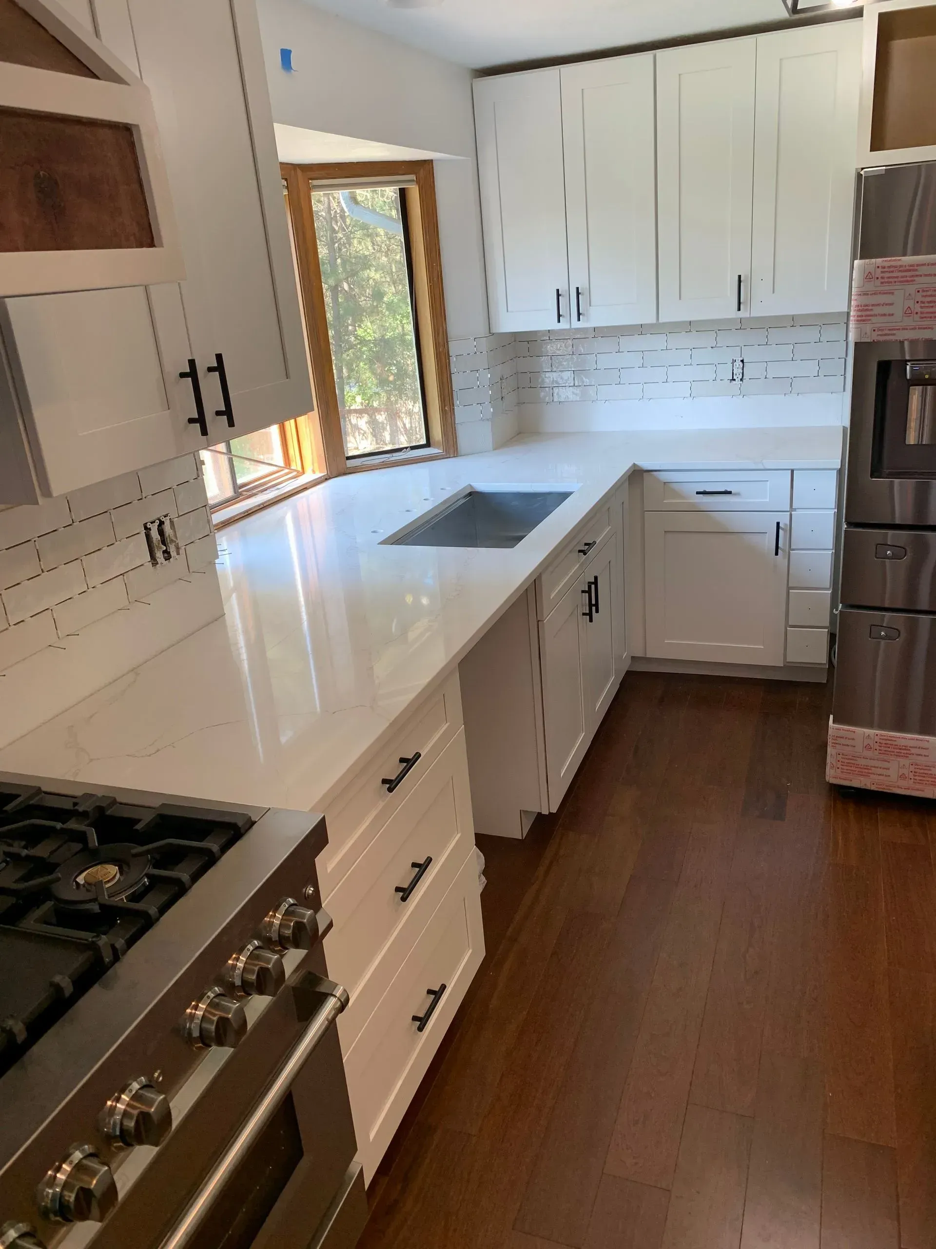 White kitchen with wood floors, countertops, cabinets, and stainless steel appliances.