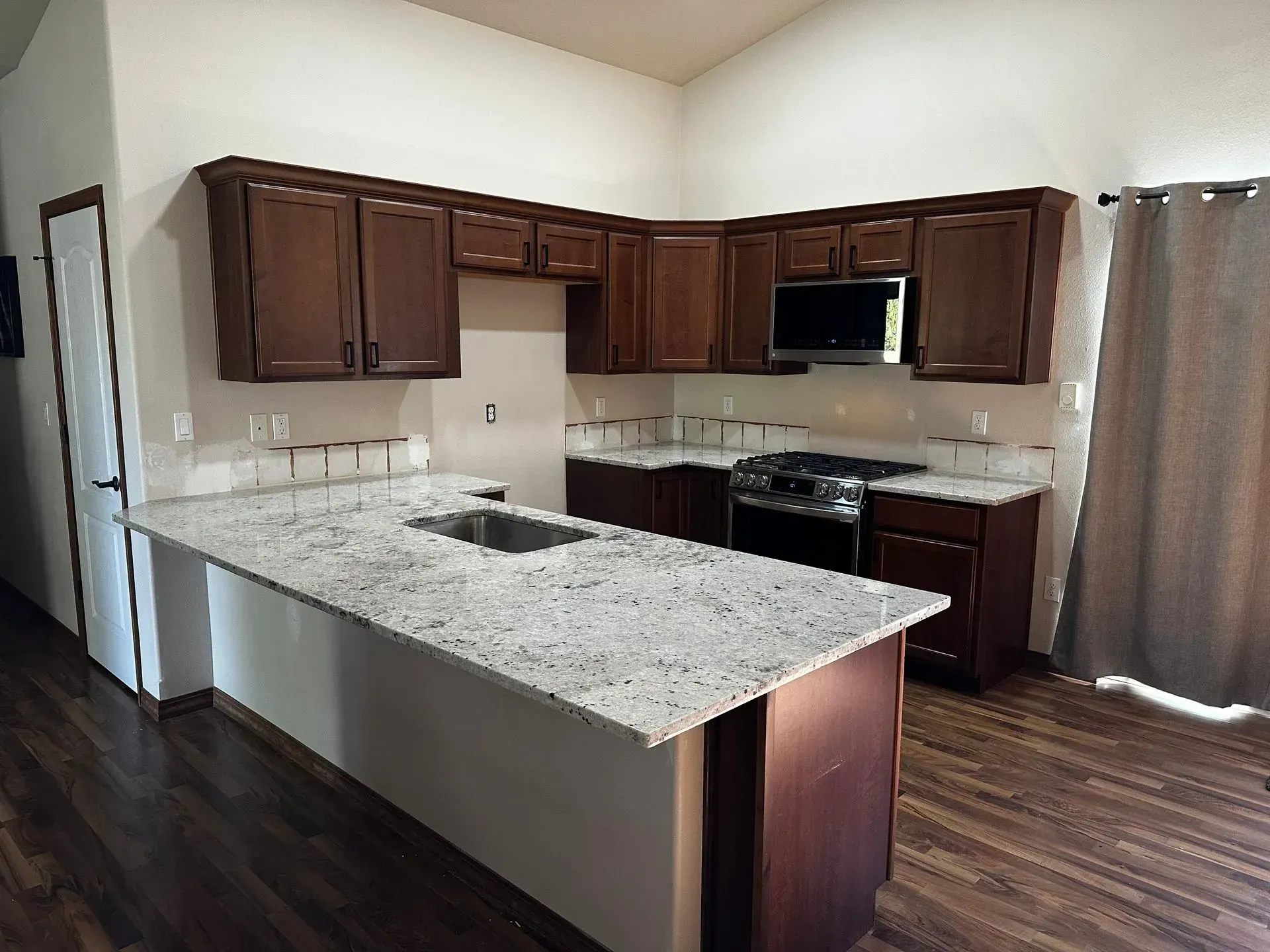 Kitchen with dark cabinets, white countertops, and stainless steel appliances.