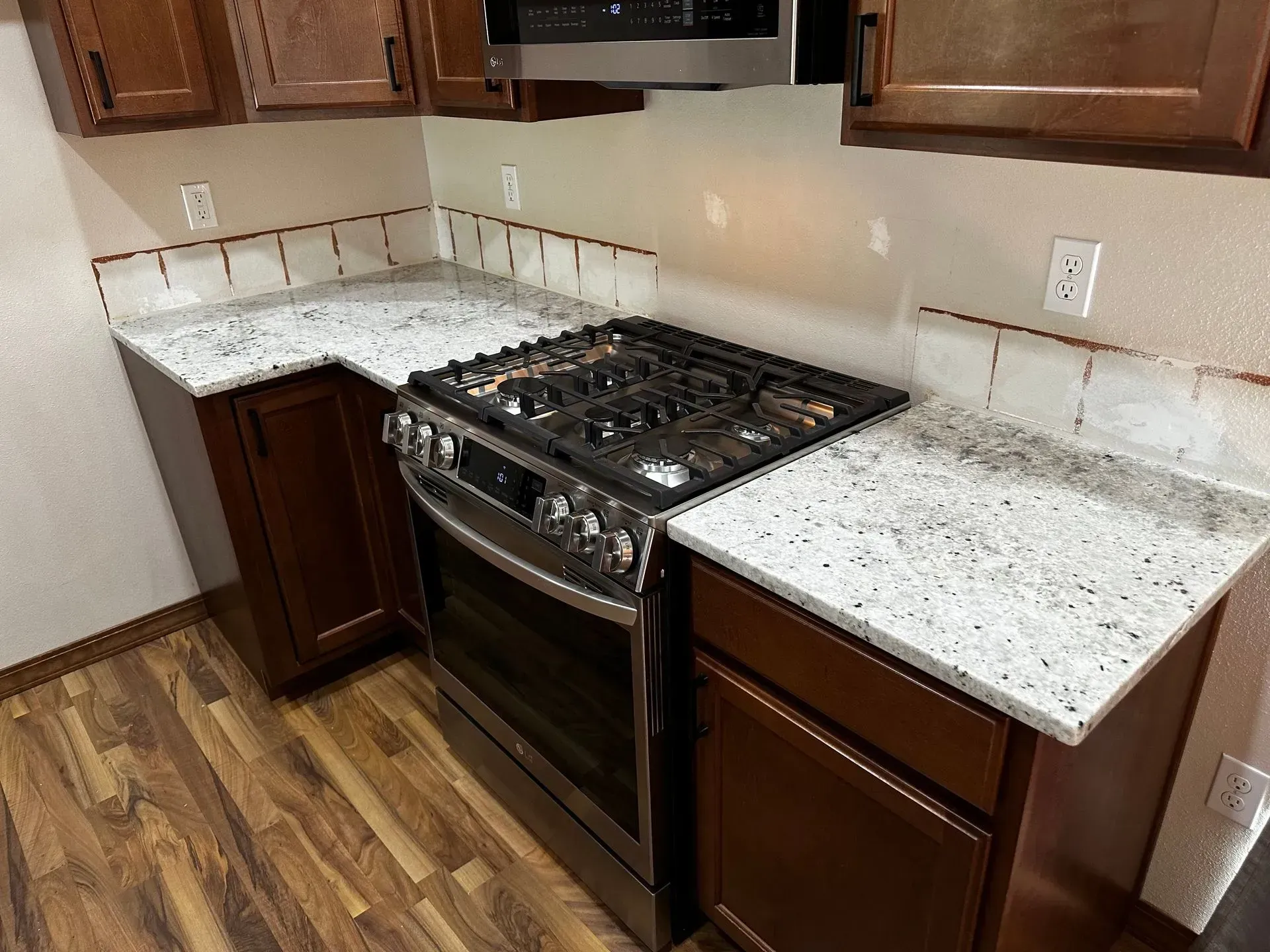 Kitchen with dark brown cabinets, a gas range, and granite countertops.