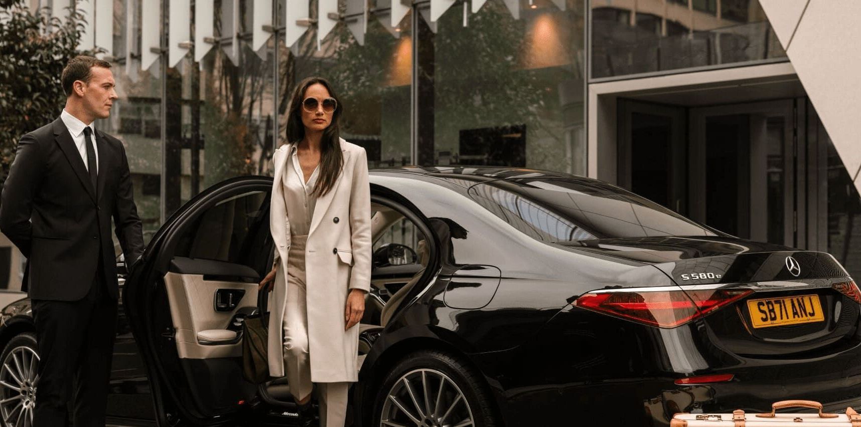 A man and a woman are standing next to a black car.