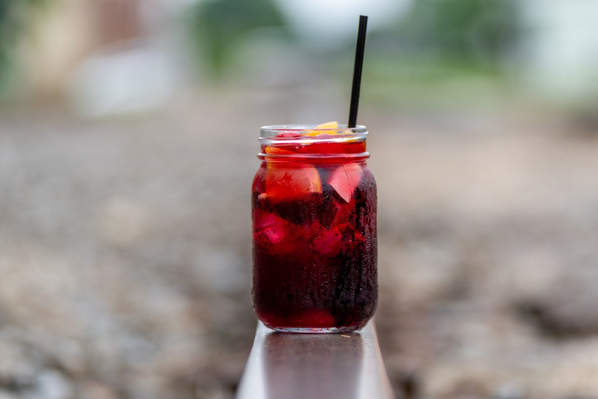 A mason jar filled with a red drink with a straw.