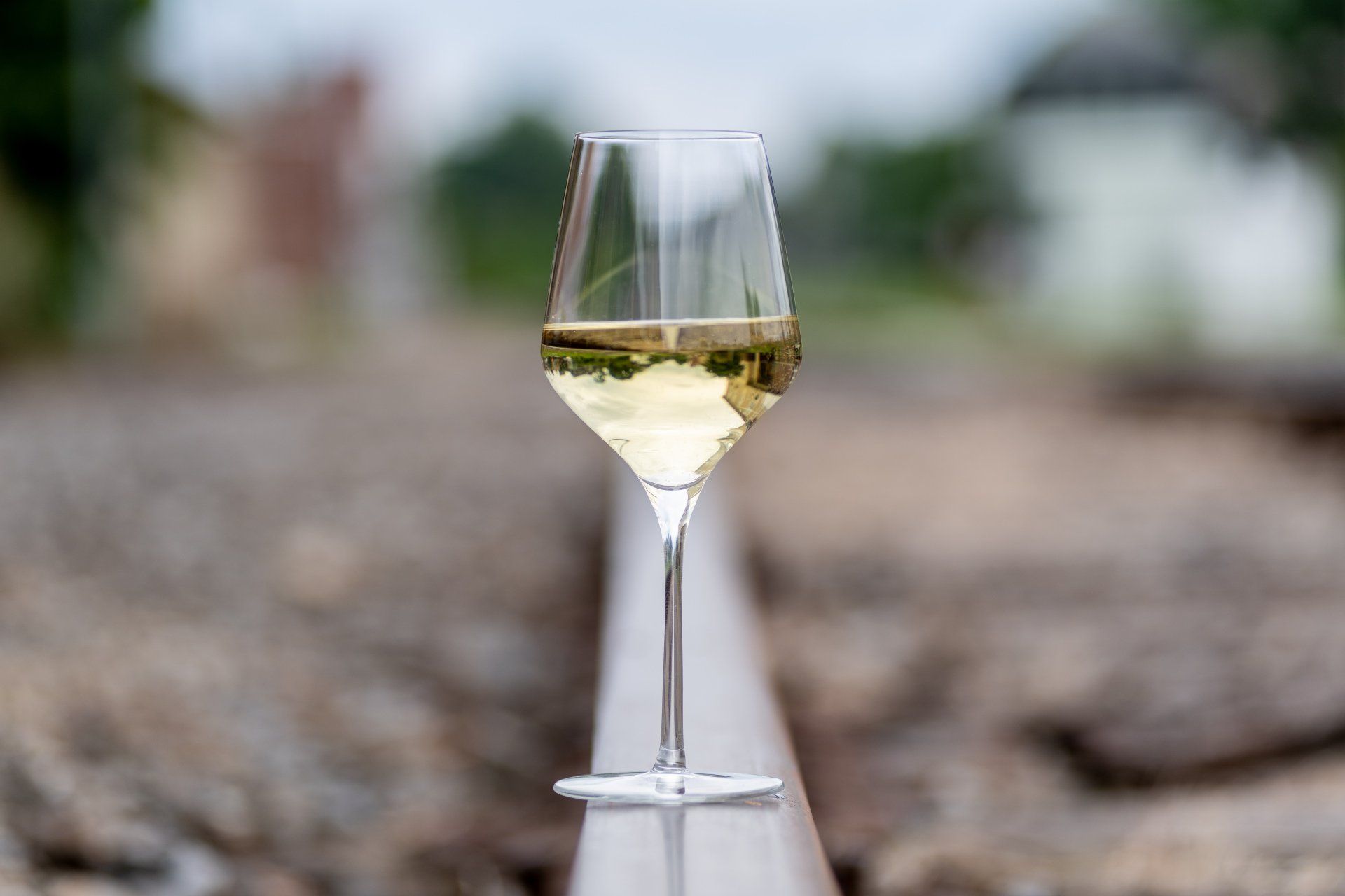 A glass of white wine is sitting on a train track.