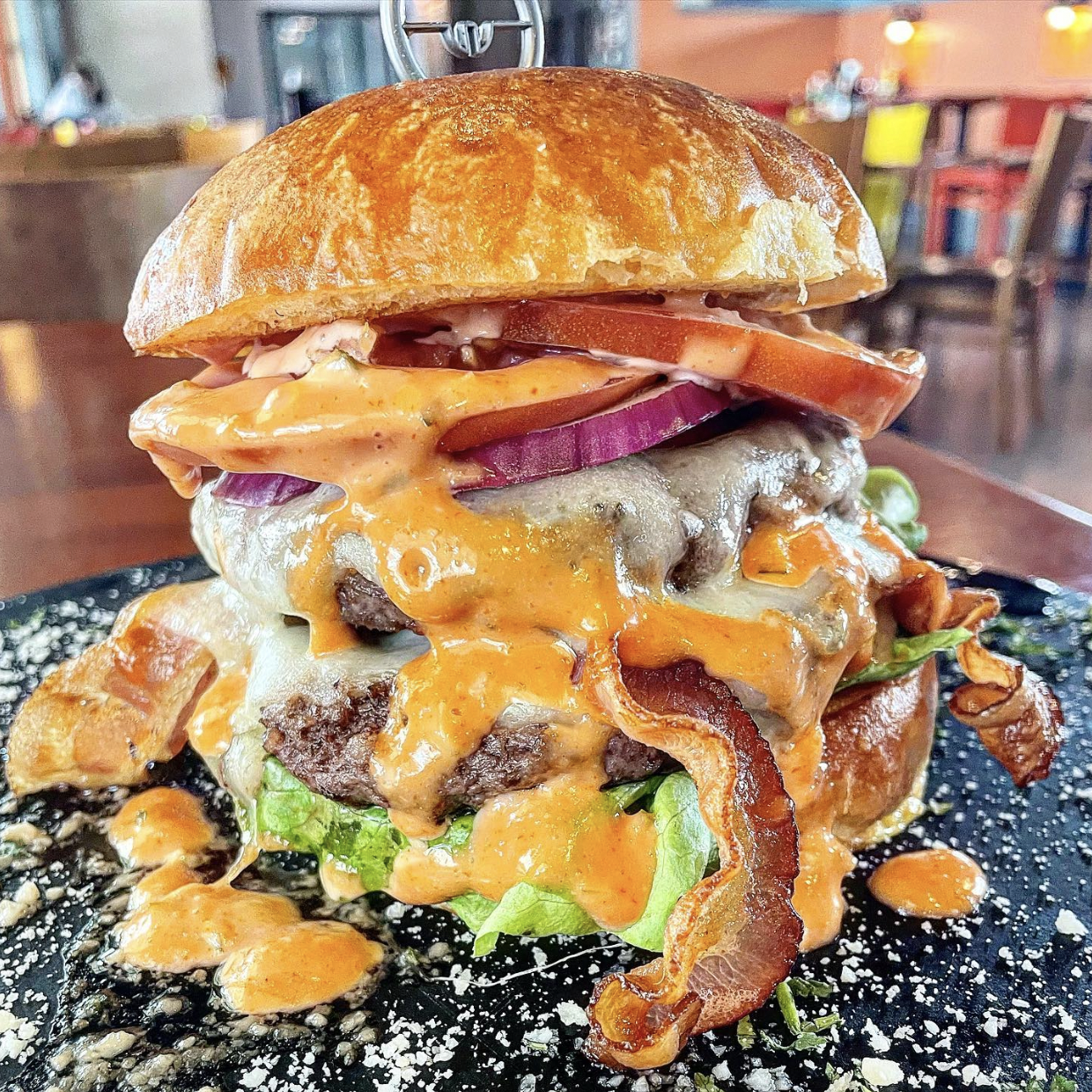 A close up of a hamburger on a plate on a table.