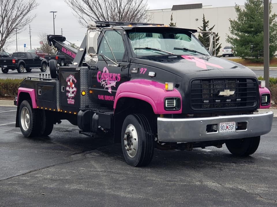 Black and pink tow truck parked in a lot, with 
