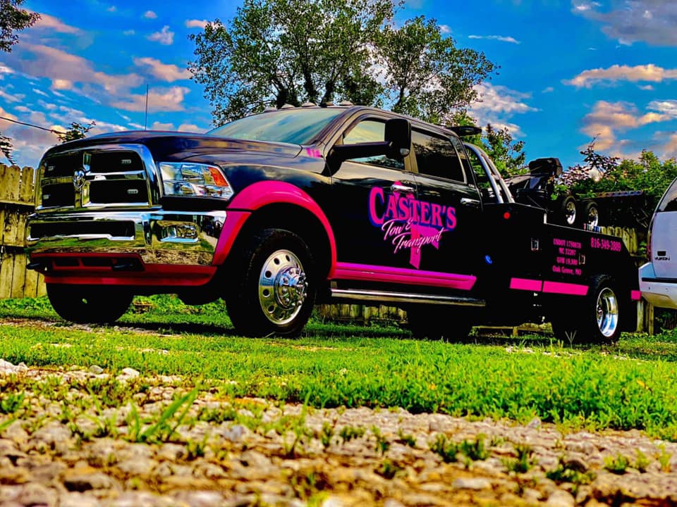 Black and pink tow truck parked on grass, with 