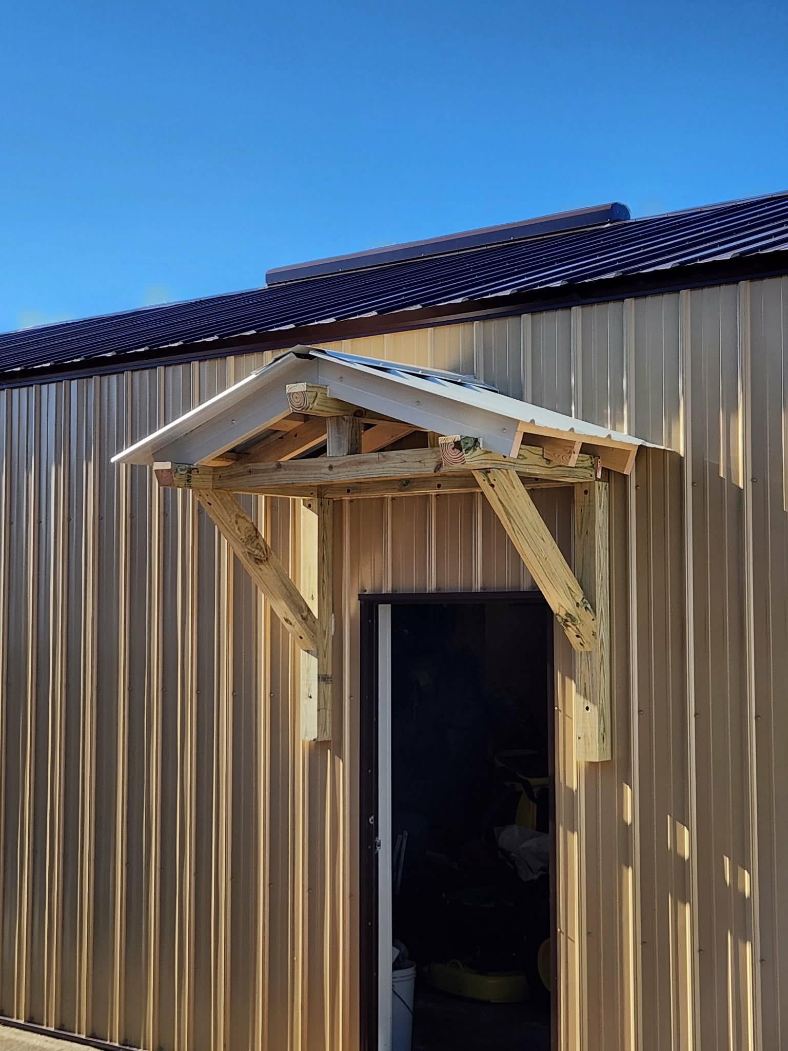 Two-story house under construction with paint cans and scaffolding in the driveway. Bright sun, blue sky.