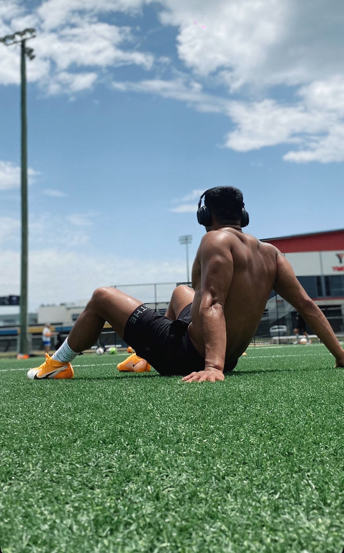 A shirtless man is laying on the grass on a field.