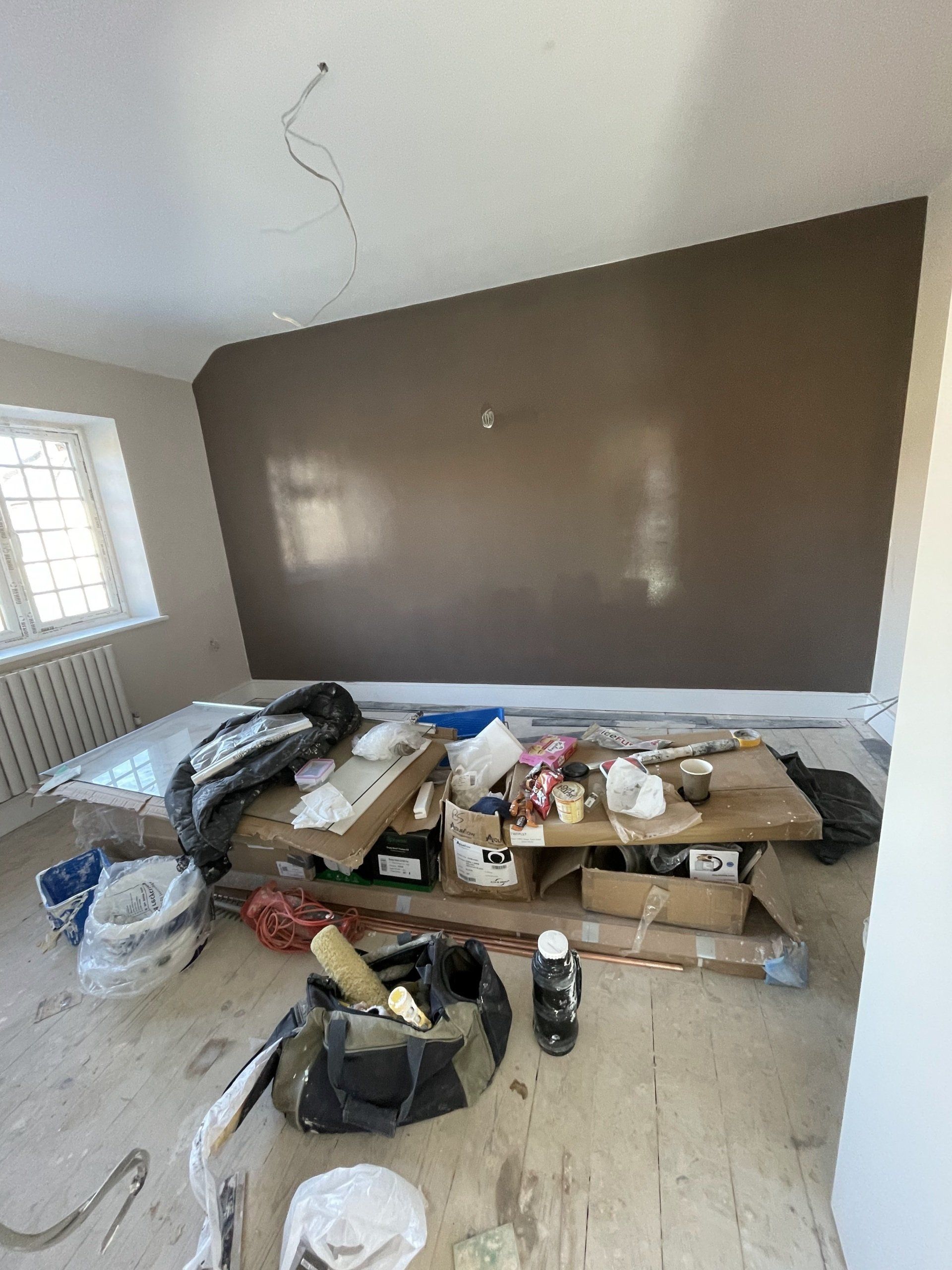 A picture of feature wall in a bedroom painted in chocolate brown by painters and decorators London