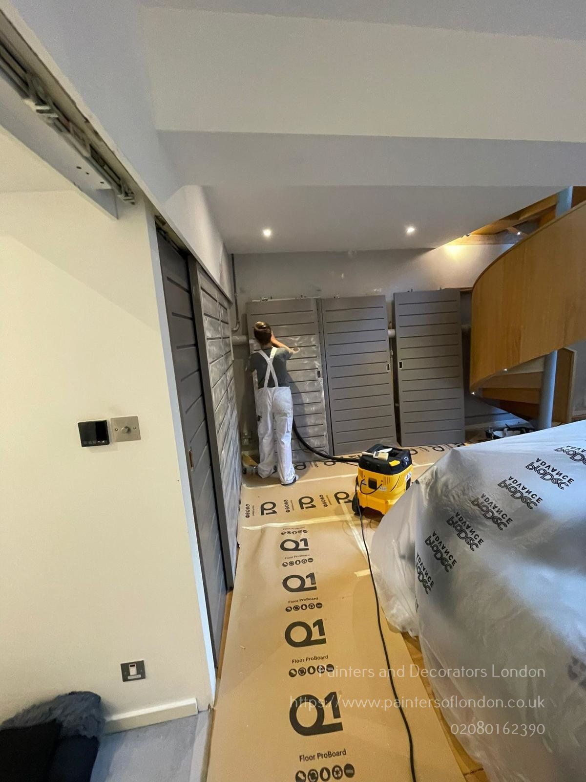 A picture of a Painter and Decorator in London painting internal doors in sage green
