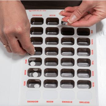 A person is putting pills into a pill organizer