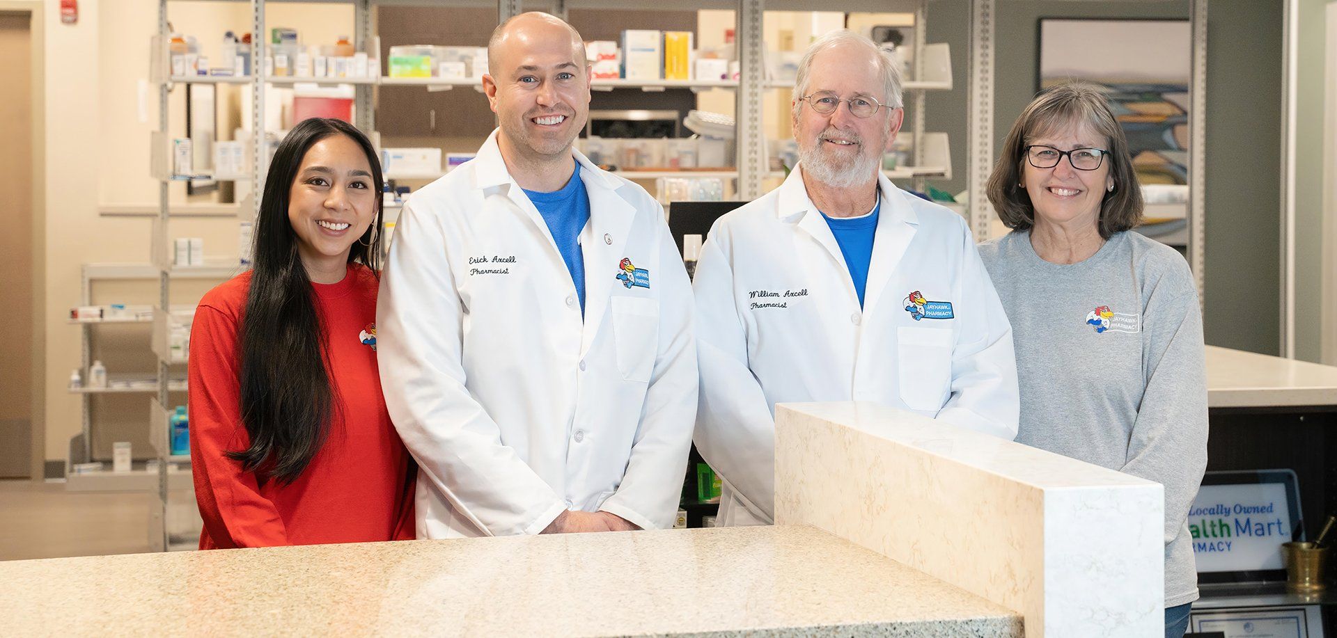 A group of doctors and nurses are posing for a picture in a pharmacy.