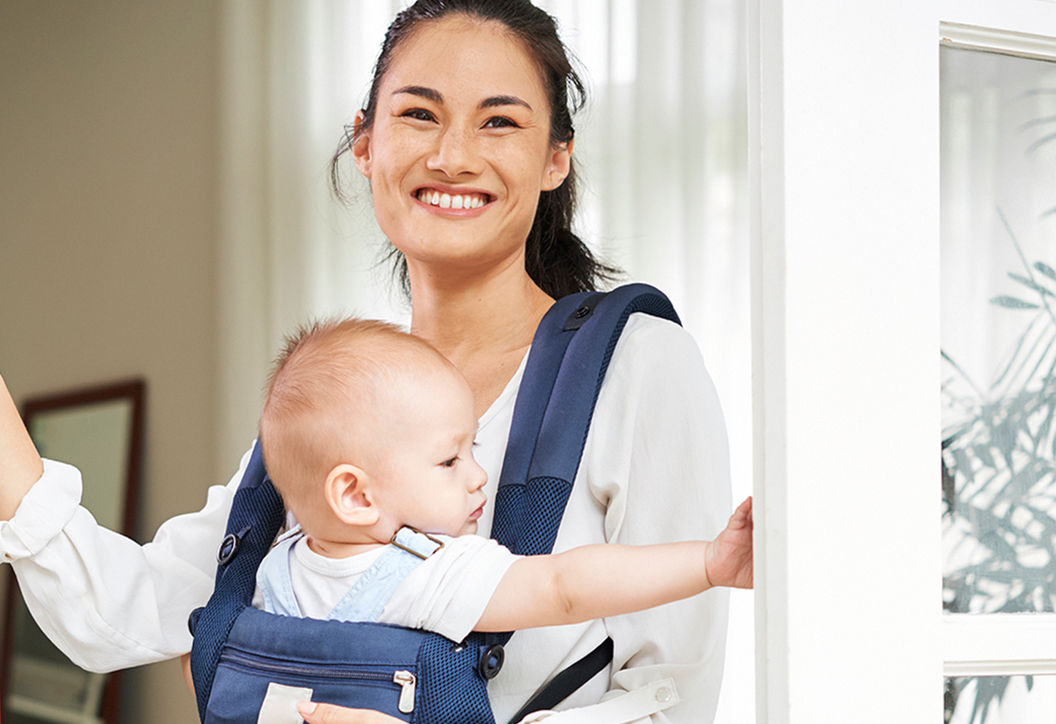 A woman is carrying a baby in a carrier.