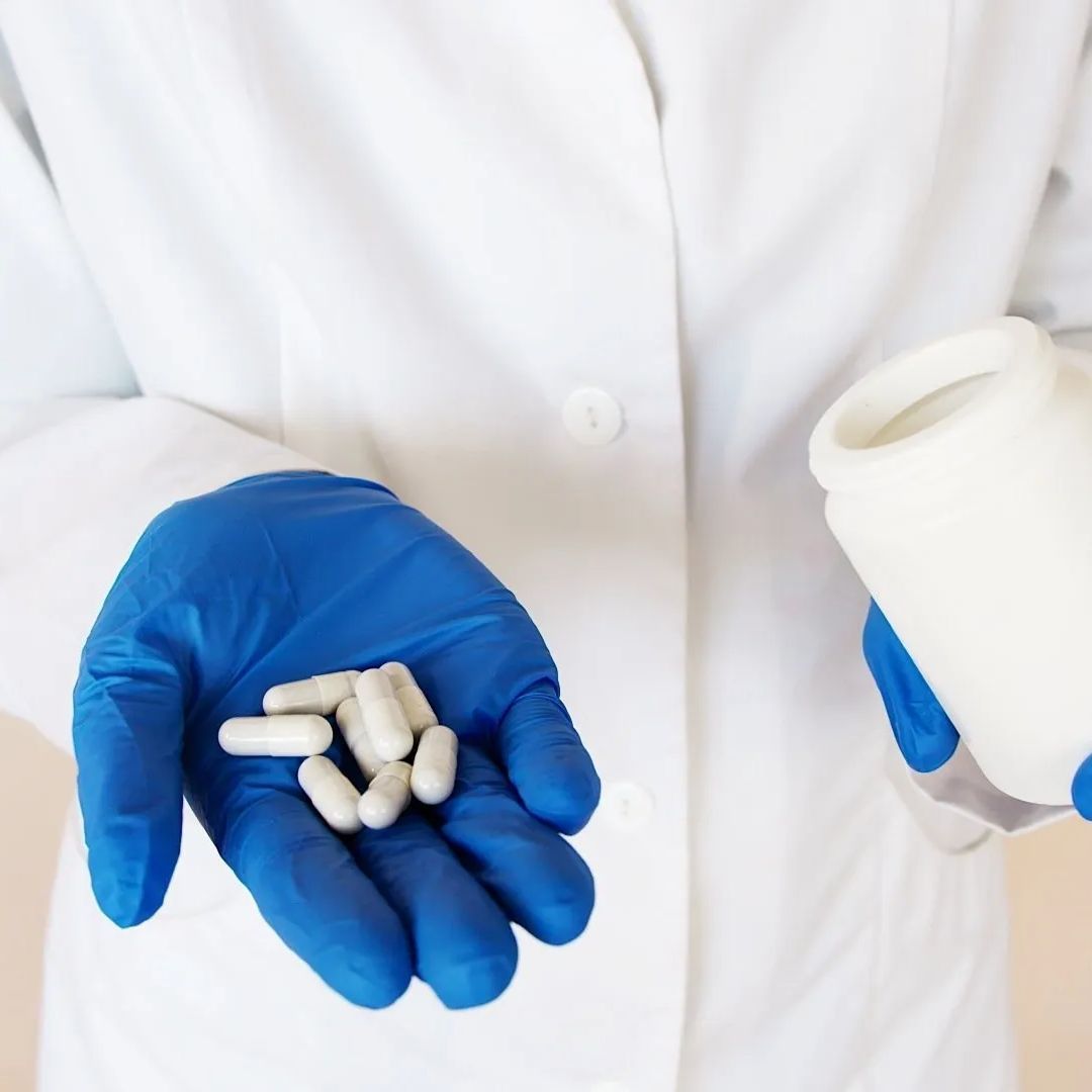 a person wearing blue gloves is holding pills in their hand