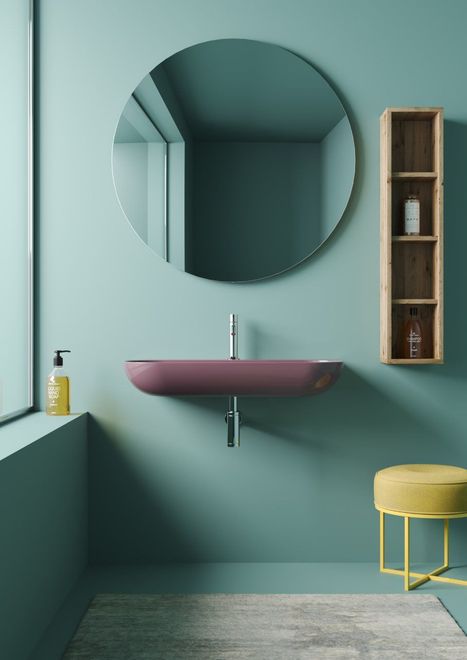 Baño con espejo redondo y pared de color verde claro