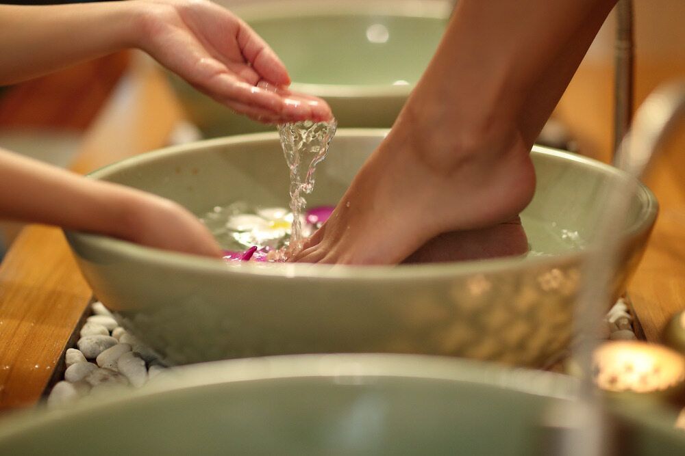 A Woman is Washing Her Feet in a Bowl of Water — Nancy's Traditional Thai Massage In Sunshine Coast, QLD