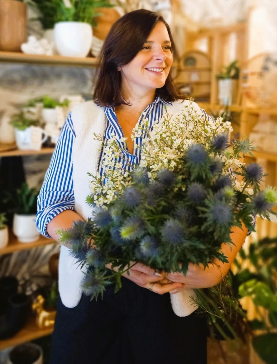 Une femme tient un bouquet de fleurs roses et blanches.