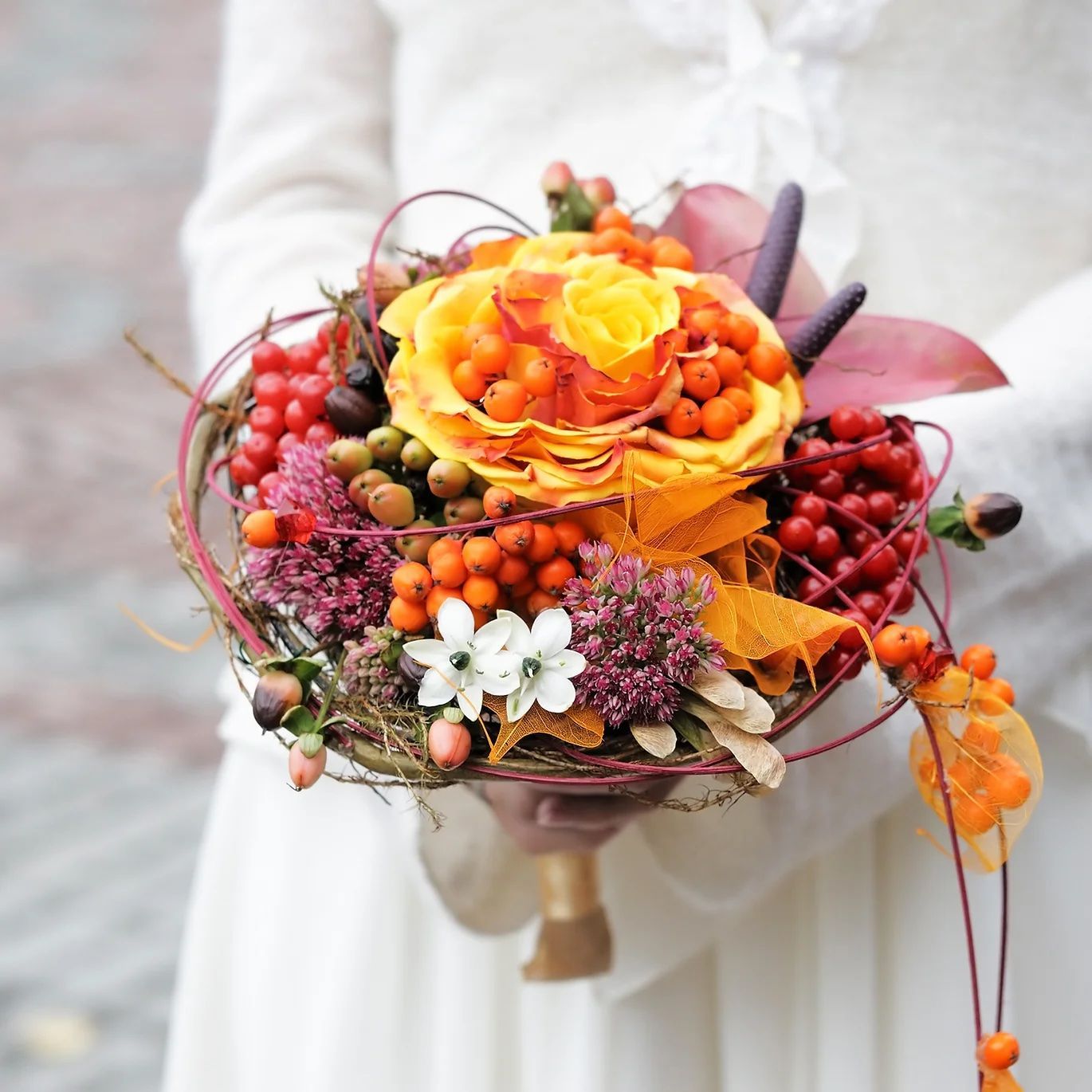 Une femme en robe blanche tient un bouquet de fleurs