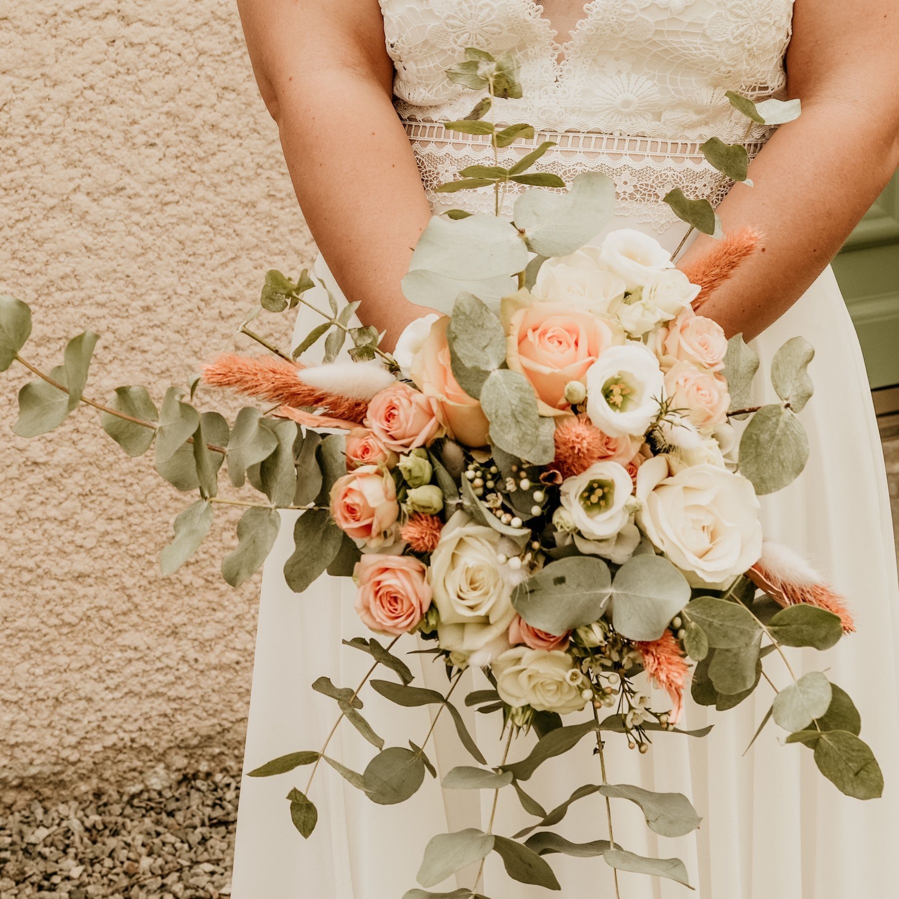 Une mariée en robe blanche tient un bouquet de fleurs.