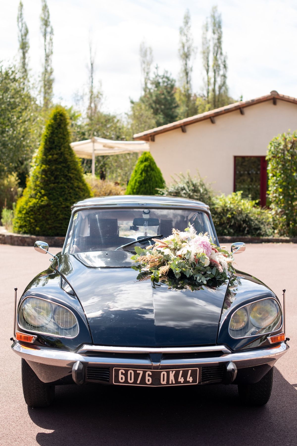 Une voiture noire avec des fleurs sur le capot est garée devant une maison.