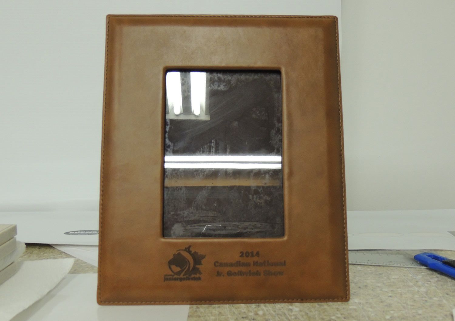 Brown leather plaque with a rectangular opening, inscription, and a logo.