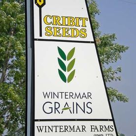 Sign for Cribit Seeds and Wintermar Grains. White panels with logos and text, with a blue sky background.