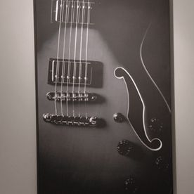 Black and white photograph of an electric guitar, close-up on the body and strings.