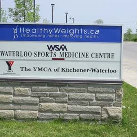 Sign for HealthyWeights, Waterloo Sports Medicine Centre, and YMCA of Kitchener-Waterloo on a stone base.