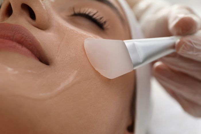 A woman is getting a facial treatment with a brush on her face.