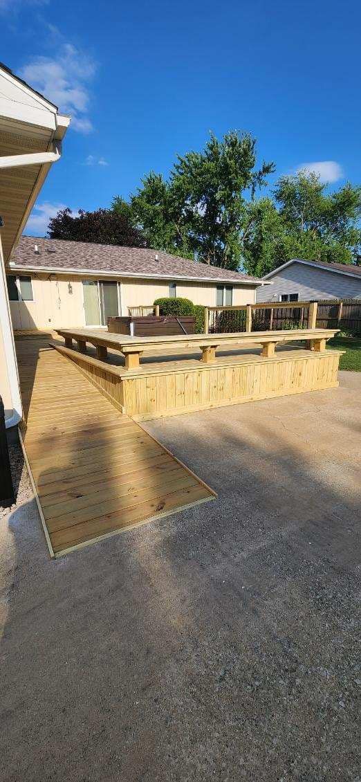 Wooden ramp and deck on a gravel surface. Buildings and trees in the background, blue sky overhead.