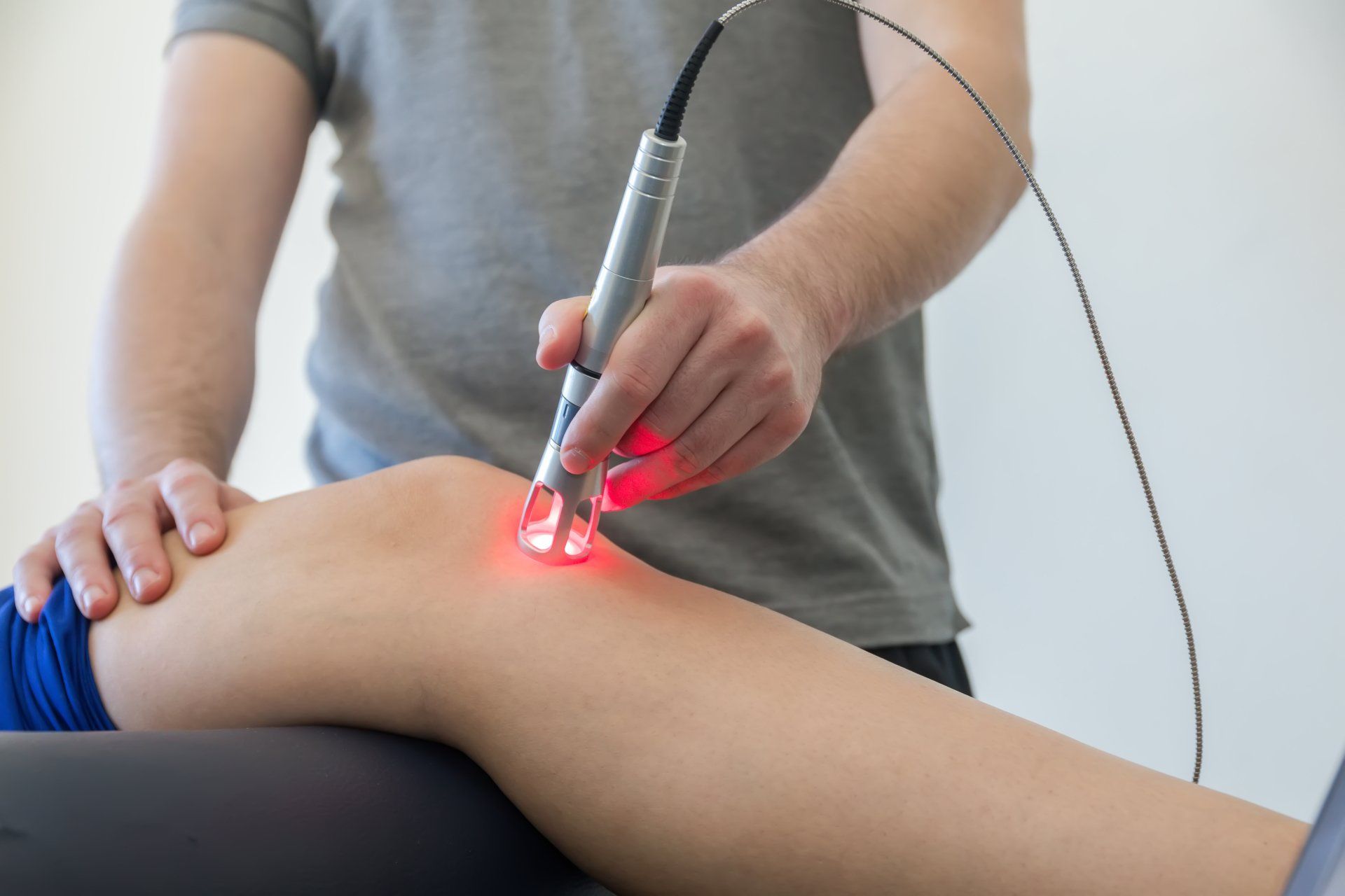 Person using a red light therapy device on a knee.