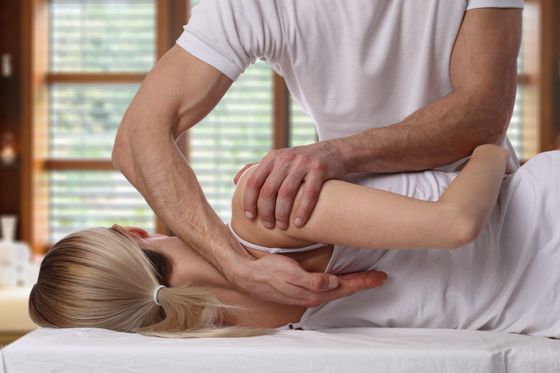 A woman on her side getting her back adjusted by a chiropractor
