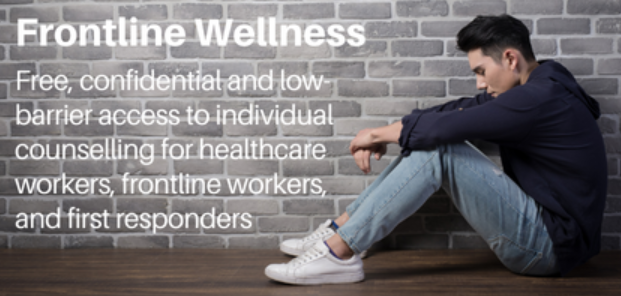 A man is sitting on the floor in front of a brick wall.