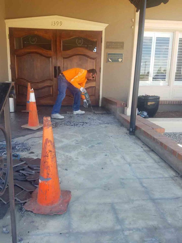 A man is working on a concrete walkway in front of a building.