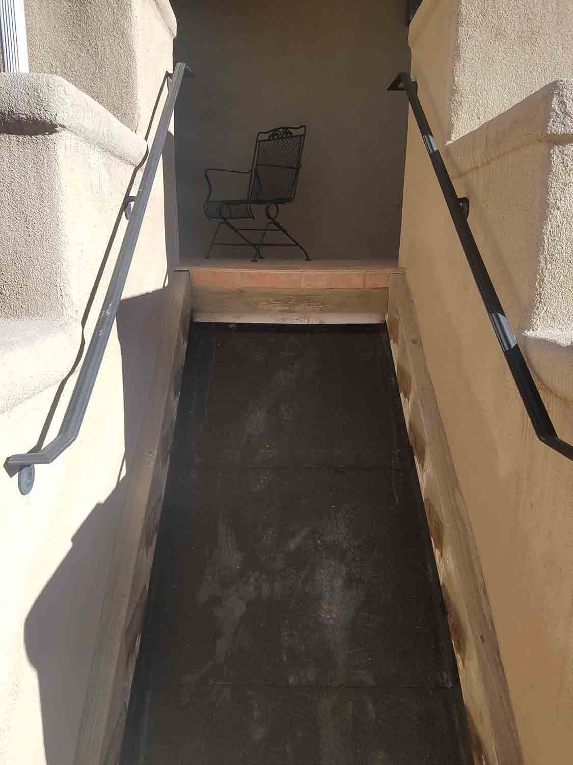 A narrow hallway with stairs and a chair in the corner.