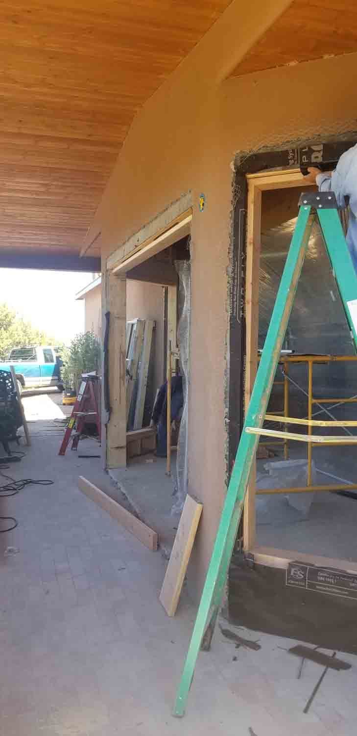 A man is standing on a ladder in front of a building under construction.