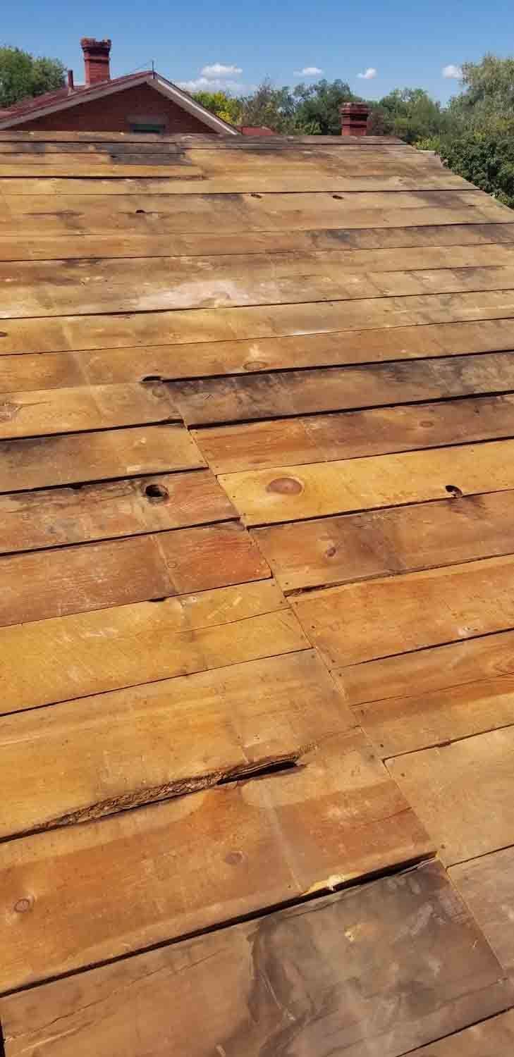 A close up of a wooden roof with a chimney in the background.
