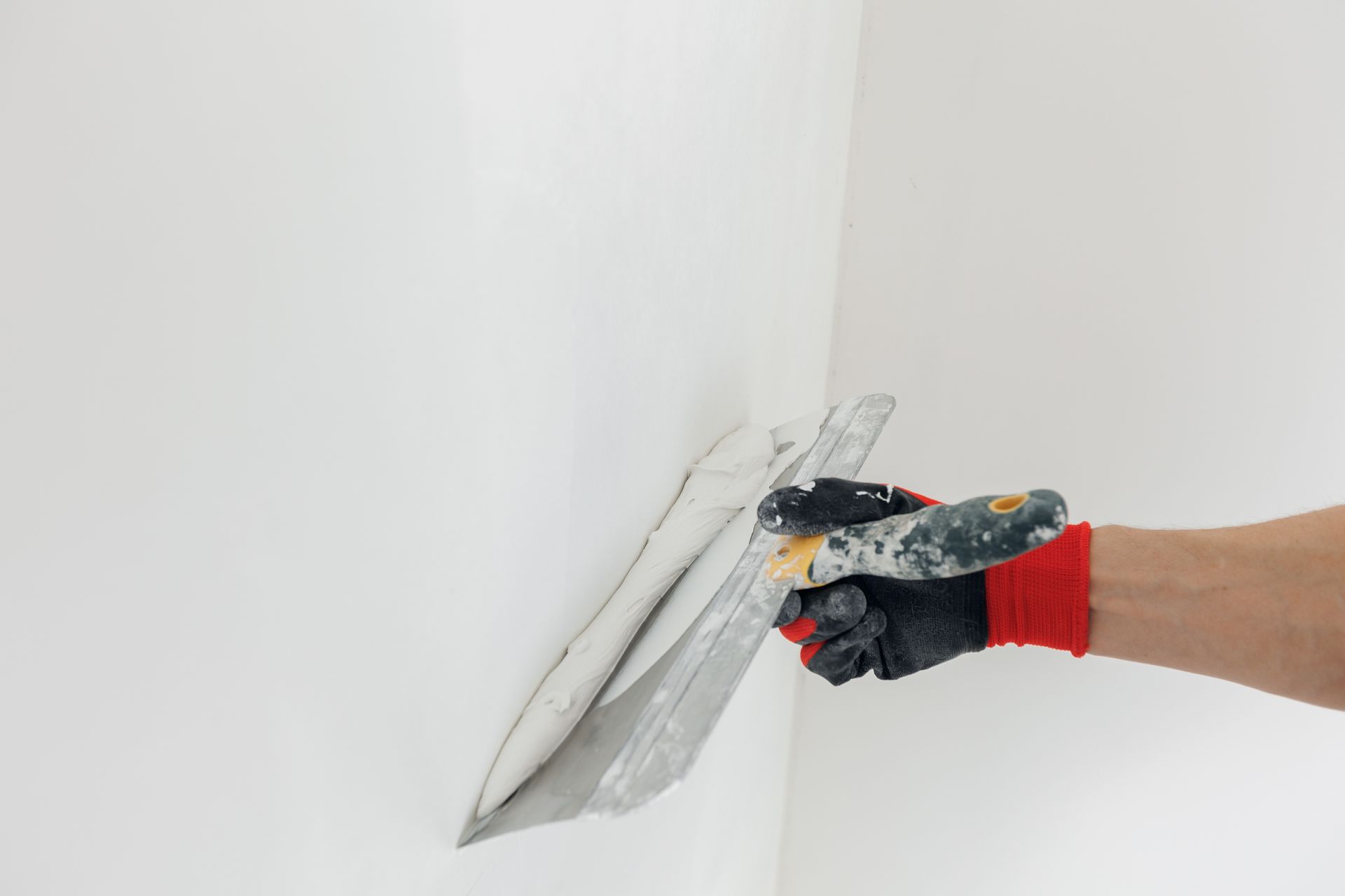 A person is plastering a wall with a trowel.