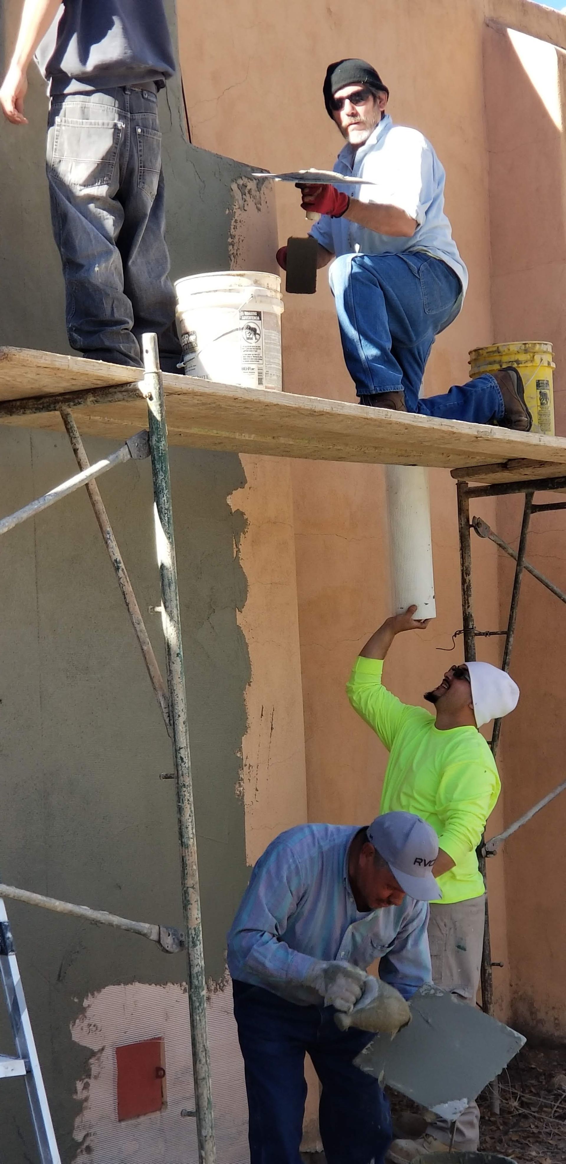 A group of construction workers are working on a wall.