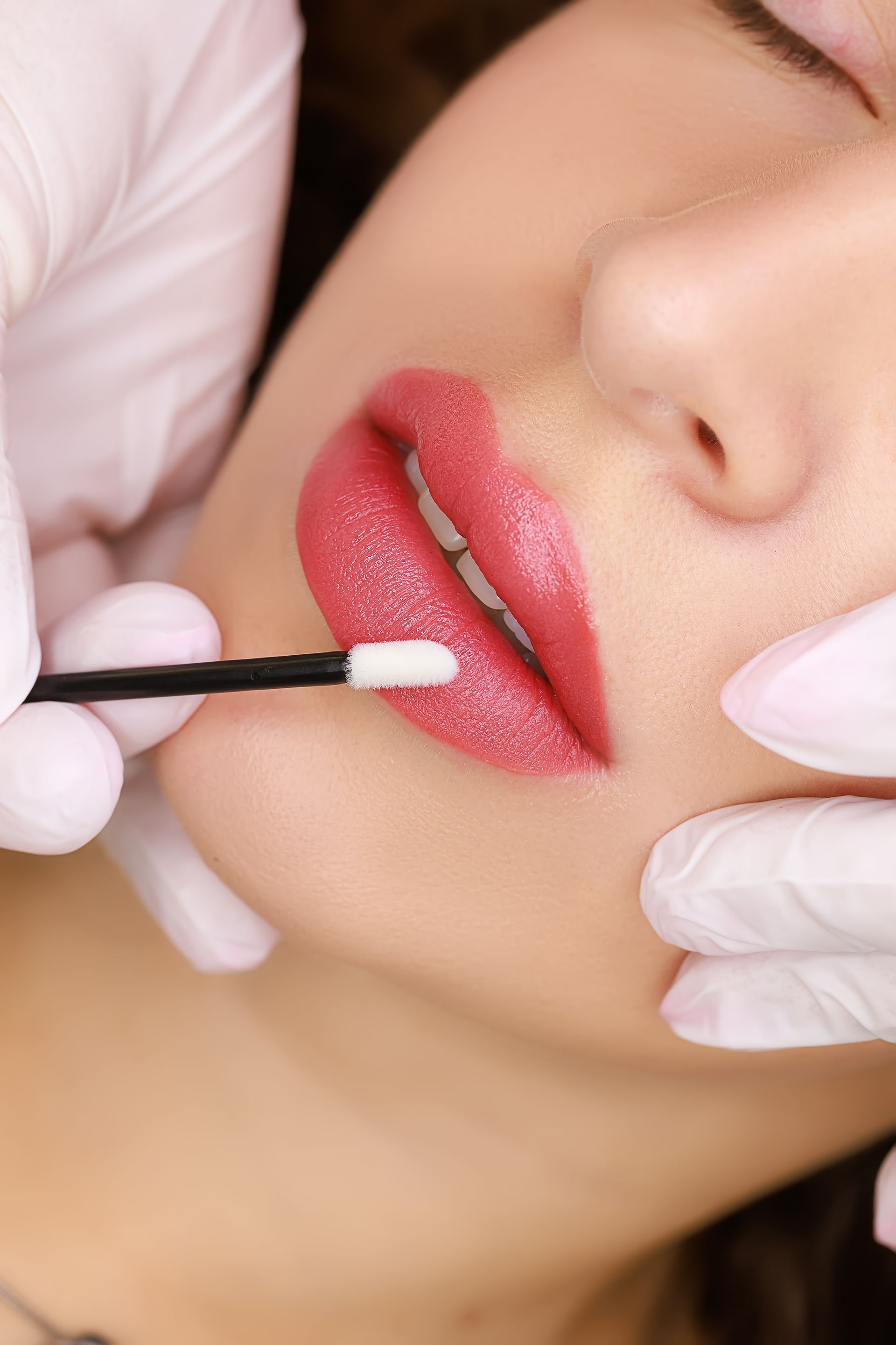 a woman getting her lips painted with a brush