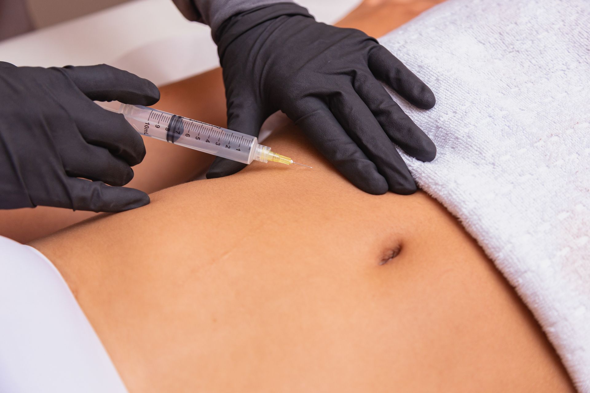 a woman is getting a fat reduction injection with a syringe