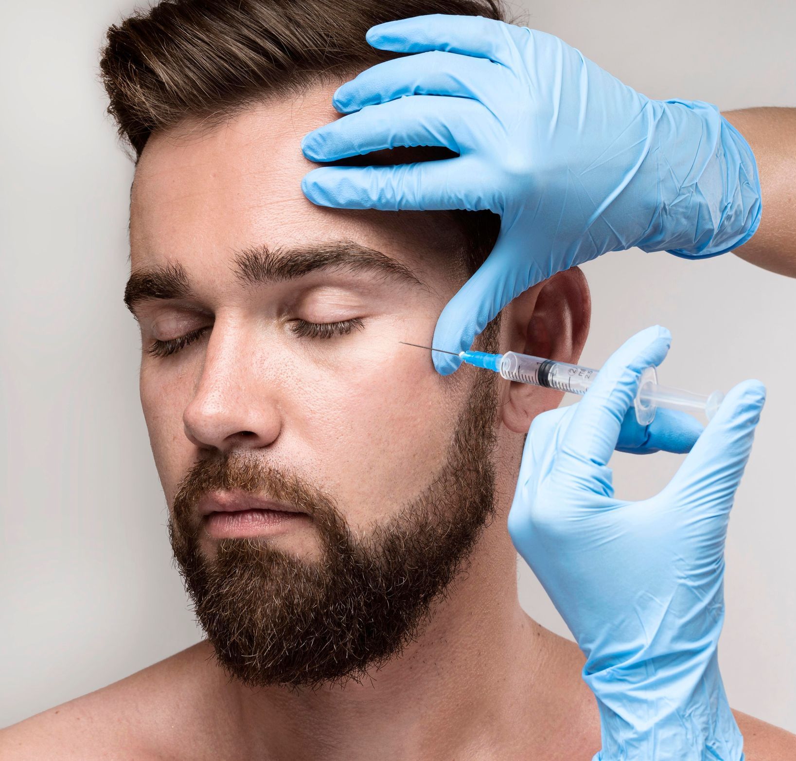 a man with a beard is getting a botox injection in his forehead