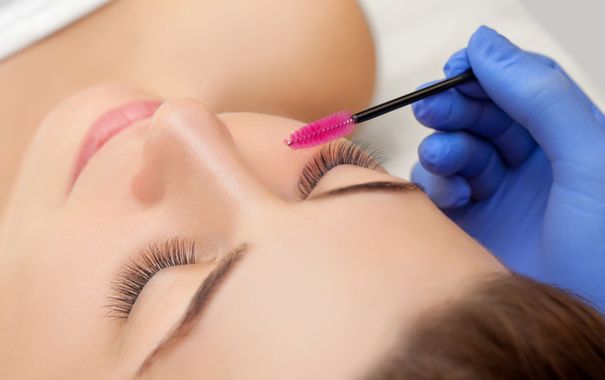 a woman is getting her eyelashes done with a pink brush